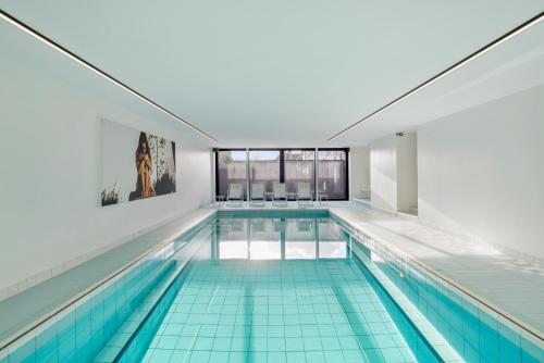 a large swimming pool with blue tiles on the floors at Villa Paradis - De ultieme kustvilla met zwembad ! in Koksijde