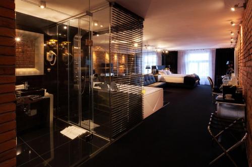 a bathroom with a glass shower and a living room at Hotel Betmanowska Main Square Residence Adults Only in Krakow