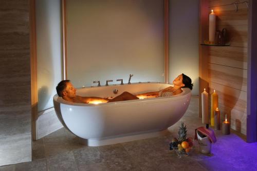 a man and woman sitting in a bath tub with candles at MOTA hotel in Livigno