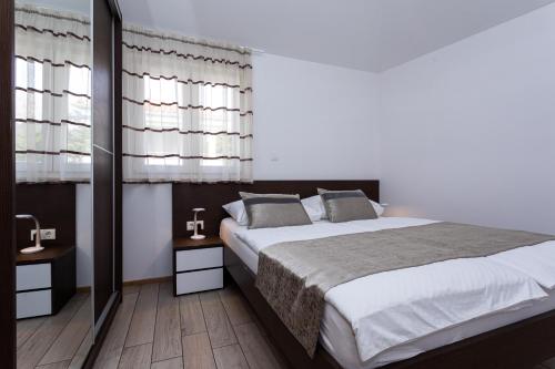 a bedroom with a large bed and two windows at Apartments Crnekovic Tomislava 8 in Baška