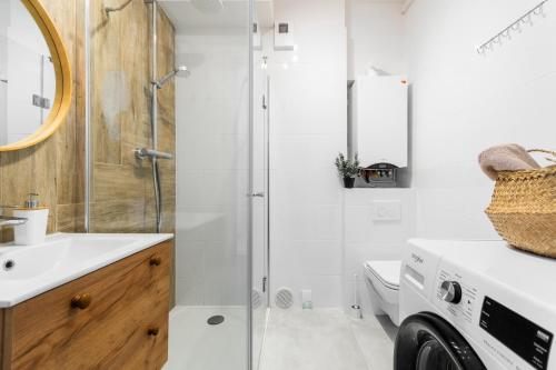 a bathroom with a shower and a washing machine at Flatbook Apartamenty - Mikoszewo Wczasowa in Mikoszewo