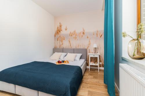 a white room with a bed with a blue blanket at Flatbook Apartamenty - Mikoszewo Wczasowa in Mikoszewo