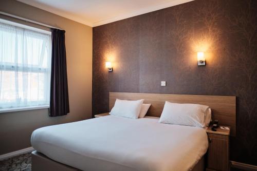 a bedroom with a large white bed and a window at Hotel De Normandie in Saint Helier Jersey
