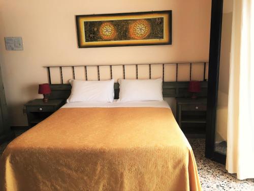 a bed with two pillows and a picture on the wall at Hotel Don Pedro in Portoscuso