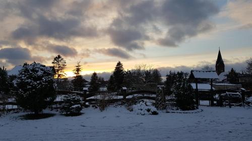 a snow covered field with a church in the distance at Dzika Chata in Nowy Barkoczyn