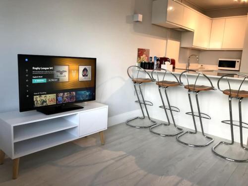 eine Küche mit zwei Barhockern und einem TV in der Unterkunft Cozy Flat in London! in London