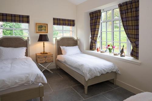 two beds in a bedroom with two windows at Coach House in Perth