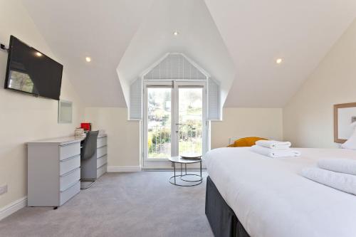 a white bedroom with a large bed and a window at Forge Bridge Cottage Coniston in Coniston