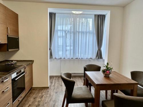 a room with a table and a kitchen with a window at SYNEK Pension in Špindlerův Mlýn