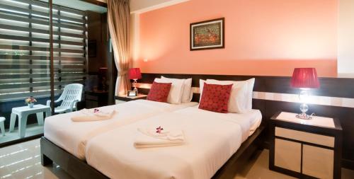 a bedroom with a large bed with white sheets and red pillows at Ratana Residence Thalang in Thalang