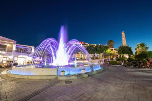a fountain with purple lights in a city at night at Li Mango in Tigaki