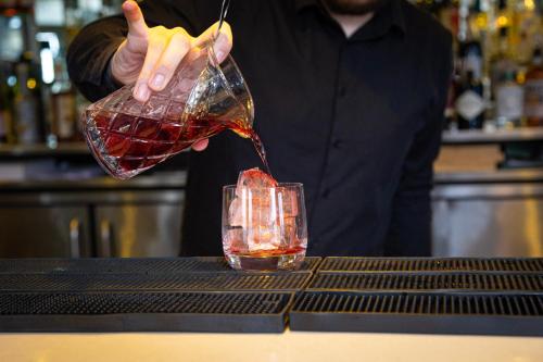 a person pouring a drink into a glass at Mannings Hotel in Truro