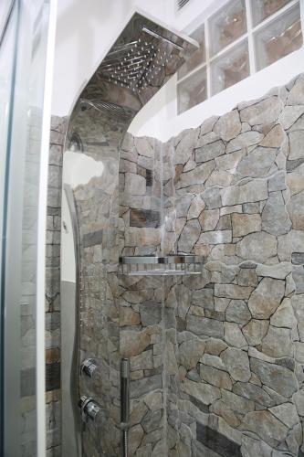 y baño con ducha de piedra y pared de piedra. en Camurría Sicily home, en Montelepre
