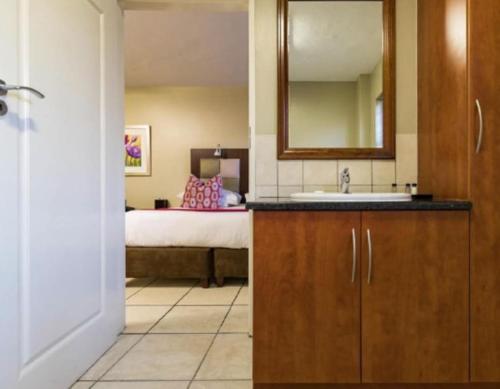 a bathroom with a sink and a bedroom with a bed at Studio Apartment in Hatfield in Pretoria