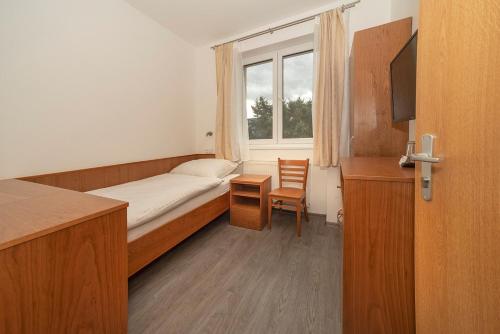 a small room with a bed and a window at Hotel Panský dům in Blovice
