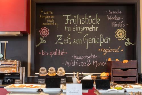 a chalkboard with writing on a wall with food on a table at Hotel einsmehr in Augsburg