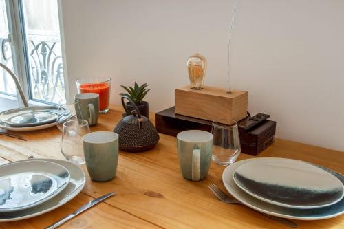 une table en bois avec des assiettes et des verres dans l'établissement Appartement Goncourt - Welkeys, à Paris