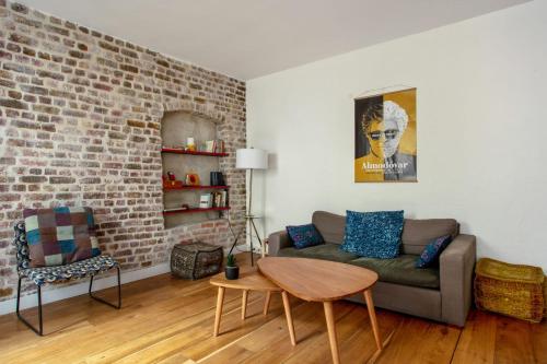 un salon avec un canapé et un mur de briques dans l'établissement Appartement Goncourt - Welkeys, à Paris
