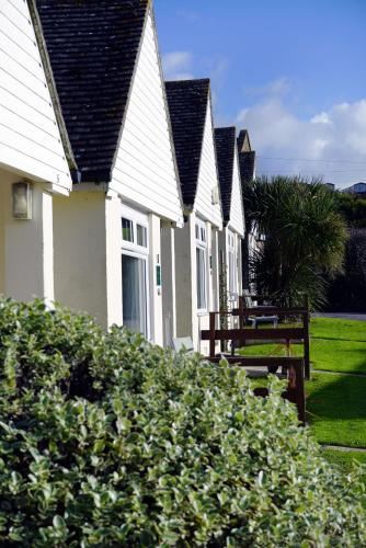 a row of houses with a bench in the grass at Golden Acre Jurassic Coastal Lodges in Bridport