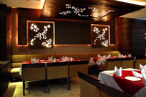 uma sala de jantar com duas mesas e cabinas com toalha de mesa vermelha e branca em HOTEL GARNET em Durg