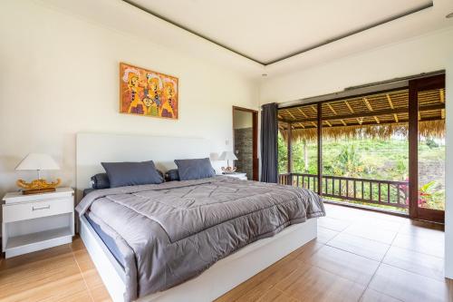 um quarto com uma cama grande e uma varanda em Pini Sentana Village Nusa Penida em Nusa Penida