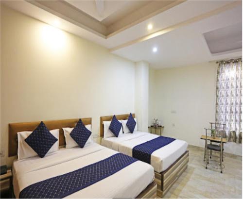 a bedroom with two beds with blue and white pillows at Hotel The Best Relax Inn By WB Inn in New Delhi
