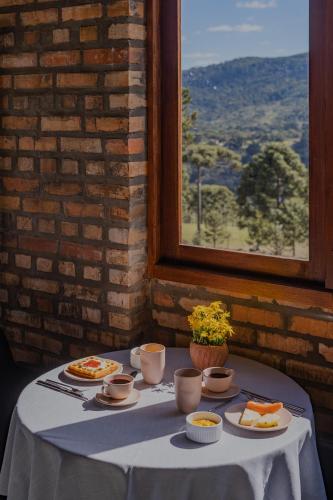 a table with plates of food on it with a window at Monte Sião Château in Urubici