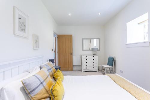 a white bedroom with a bed and a dresser at South Barlogan Farm in Bridge of Weir