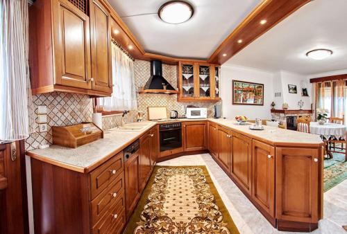 a large kitchen with wooden cabinets and a rug at Διαμέρισμα τρίτου ορόφου στην Δαύλεια με θέα in Dhávlia