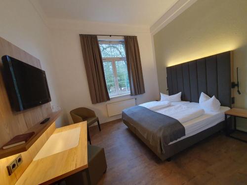 a hotel room with a bed and a flat screen tv at Gasthaus & Hotel Grünhof in Frankfurt Oder