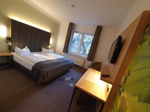 フランクフルト・アン・デア・オーダーにあるGasthaus & Hotel Grünhofのベッドとテレビが備わるホテルルームです。