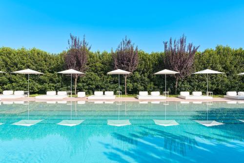 a swimming pool with white chairs and umbrellas at Ramo d'Aria Etna Boutique Hotel in Giarre