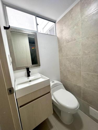 uma casa de banho com um WC, um lavatório e um espelho. em Apartamento amoblado cerca al aeropuerto em Pereira