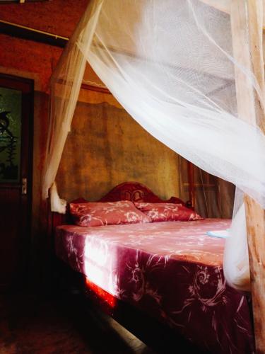 a bedroom with a bed with a mosquito net at Hidden Well Hiriketiya in Hiriketiya
