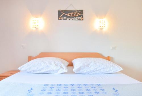 two pillows on a bed with two lights on the wall at Apartments Antonija Pirovac in Pirovac