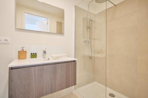 La salle de bains est pourvue d'un lavabo et d'une douche en verre. dans l'établissement Diamant 3 Bedroom, à Bruxelles