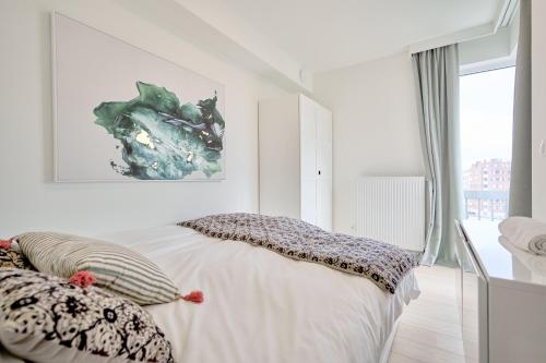 een witte slaapkamer met een bed met kussens erop bij Diamant 3 Bedroom in Brussel