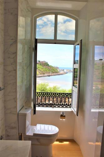 a bathroom with a toilet and a large window at KAZARÃO DI MAVETE- Guesthouse in Praia