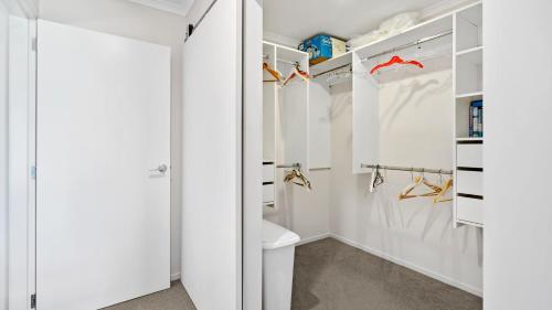 vestidor blanco con aseo y puerta en The Lakehouse - Tauranga Holiday Home en Tauranga