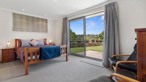 タウランガにあるThe Lakehouse - Tauranga Holiday Homeのベッドルーム1室(ベッド1台付)、スライド式ガラスドアが備わります。