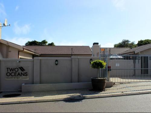 a fence with a sign on it next to a street at Two Oceans Stay in Cape Town