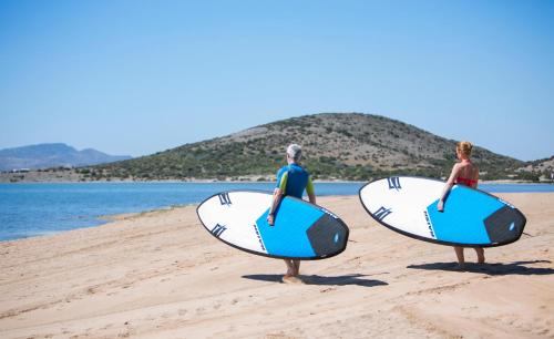 duas pessoas estão de pé na praia com pranchas de surf em Poseidon La Manga Hotel & Spa - Designed for Adults em La Manga del Mar Menor