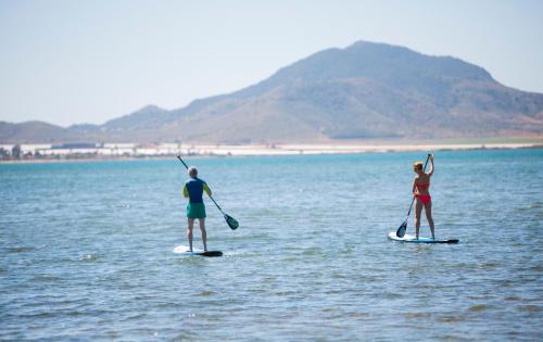 2 personnes sont debout sur des planches de paddle dans l'eau dans l'établissement Poseidon La Manga Hotel & Spa - Designed for Adults, à La Manga del Mar Meno