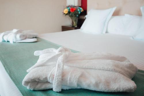 una pila de toallas blancas sentadas en una cama en Poseidon La Manga Hotel & Spa - Designed for Adults, en La Manga del Mar Menor