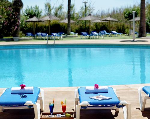 two blue and white lounge chairs and a swimming pool at Hotel Playas de Guardamar in Guardamar del Segura