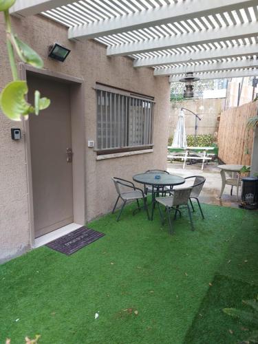 a patio with a table and chairs on the grass at YasmeN suite in Mas'ade