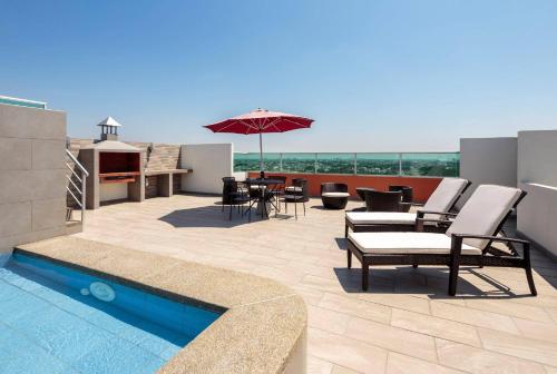 a patio with a pool and chairs and an umbrella at 2 room department (5 people). Private exclusive area in Guayaquil in Guayaquil