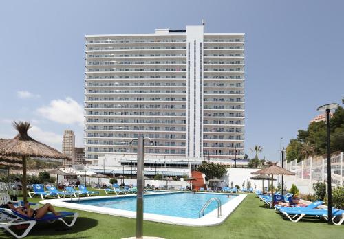 een hotel met een zwembad en een hoog gebouw bij Hotel Poseidon Playa in Benidorm
