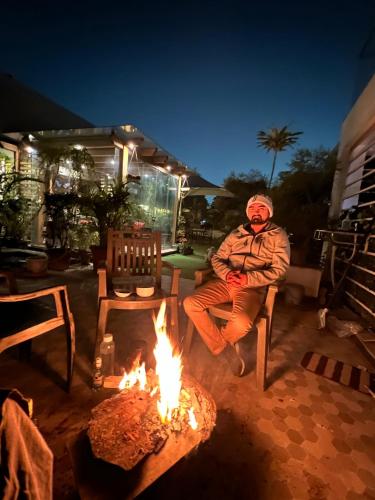 a man sitting on a bench next to a fire at GREEN HOME STAY in Lucknow