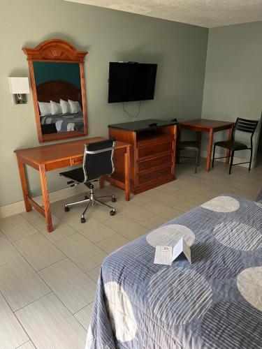 a hotel room with a bed and a desk and a television at Brandon Motor Lodge in Brandon